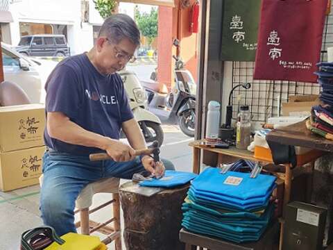 许胜凯为帆布包钉上扣环。（郑佩雯拍摄）