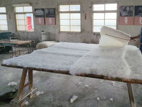 蔡顺龙铺棉功夫精湛，他说这是手工被舒适耐用的关键，要纵横交错、中间厚四边薄，才能贴合人体，达到保暖效果。（郑佩雯拍摄）