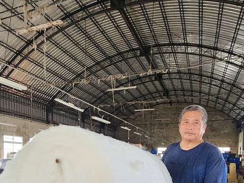 成团的棉花放进梳棉机会被梳理成一卷棉片，捆在竹竿上就像是巨大棉花糖。（郑佩雯拍摄）