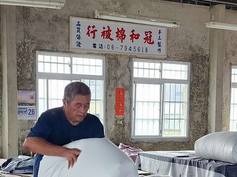 蔡顺龙在铺好的棉花放上防沾布，套上内胎被套，从角落往中间折後，再快速翻出及整型。（郑佩雯拍摄）