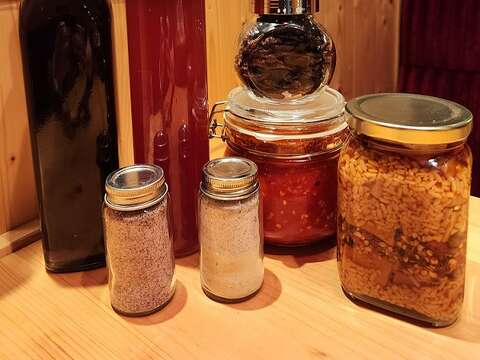 丮硠‧玛那制作的树葡萄酒、台湾紫苏气泡饮、发酵乾辣椒、发酵辣椒酱、米麴豆腐乳(後排由左到右)。前排则是用来增添食物风味的紫苏盐、紫苏盐混橘皮盐。（郑佩雯拍摄）