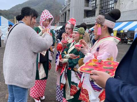 身着传统服饰的表演团体成员於台南观光摊位体验特色试吃活动,透过美食交流加深对台南的认识。