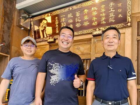 筑馨居豆花店的价目表由书艺家郑有懋（右）题字，知名木雕艺师刘进文（左）以「茄苳入石柳」技法打造，兼具艺术与工艺价值。（张耘书拍摄）