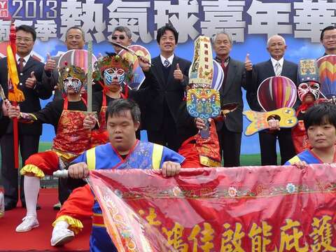 贵宾手持热气球板与身心障碍表演团体合影，象徵爱在台南希望起飞