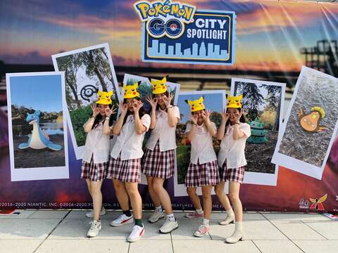 "People wearing paper hats take a group photo in front of the main vision"